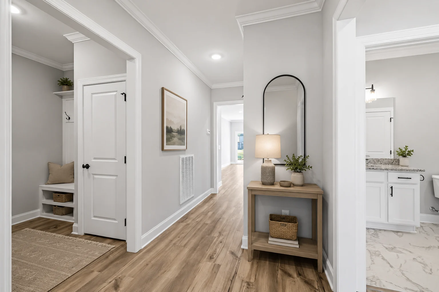 Elegant hallway by Pratt Home Builders in Chattanooga TN, featuring wood flooring, a console table with a lamp, and an adjoining bathroom.