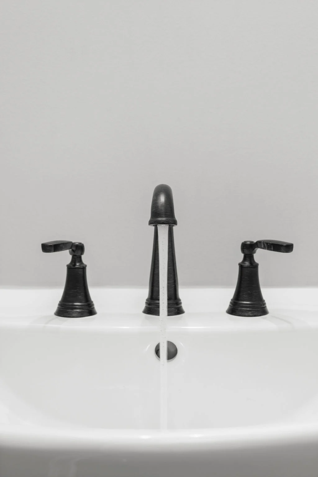 Sleek black faucet with flowing water in a modern sink, designed by Pratt Home Builders in Chattanooga TN.