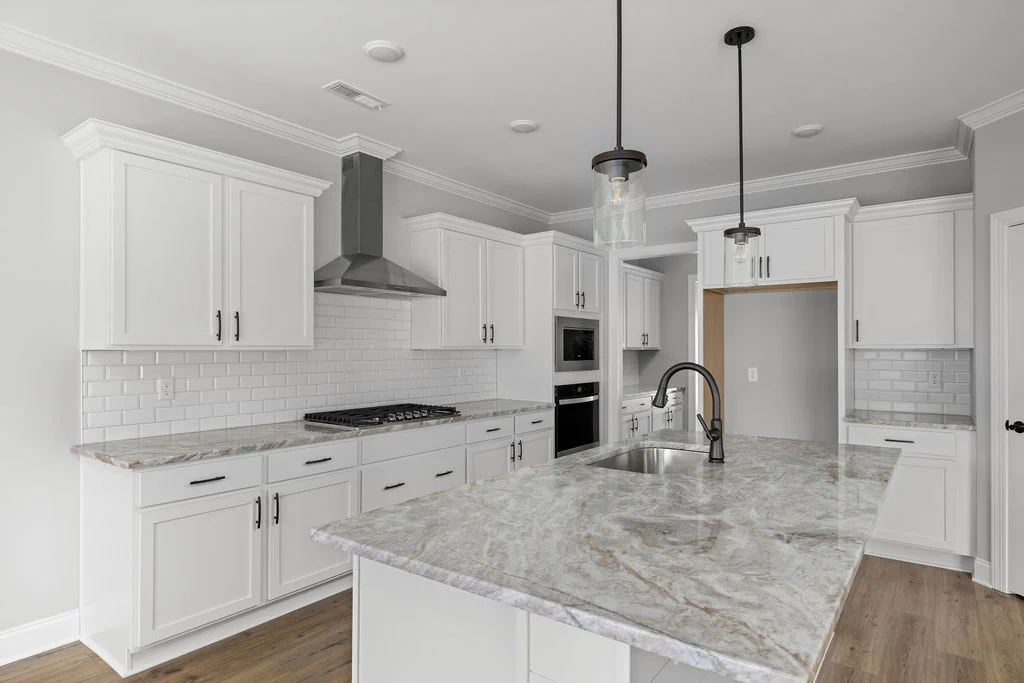 Home for sale. Modern kitchen with white cabinets, marble countertops, and stainless steel appliances. Designed by Pratt Home Builders in Chattanooga TN.