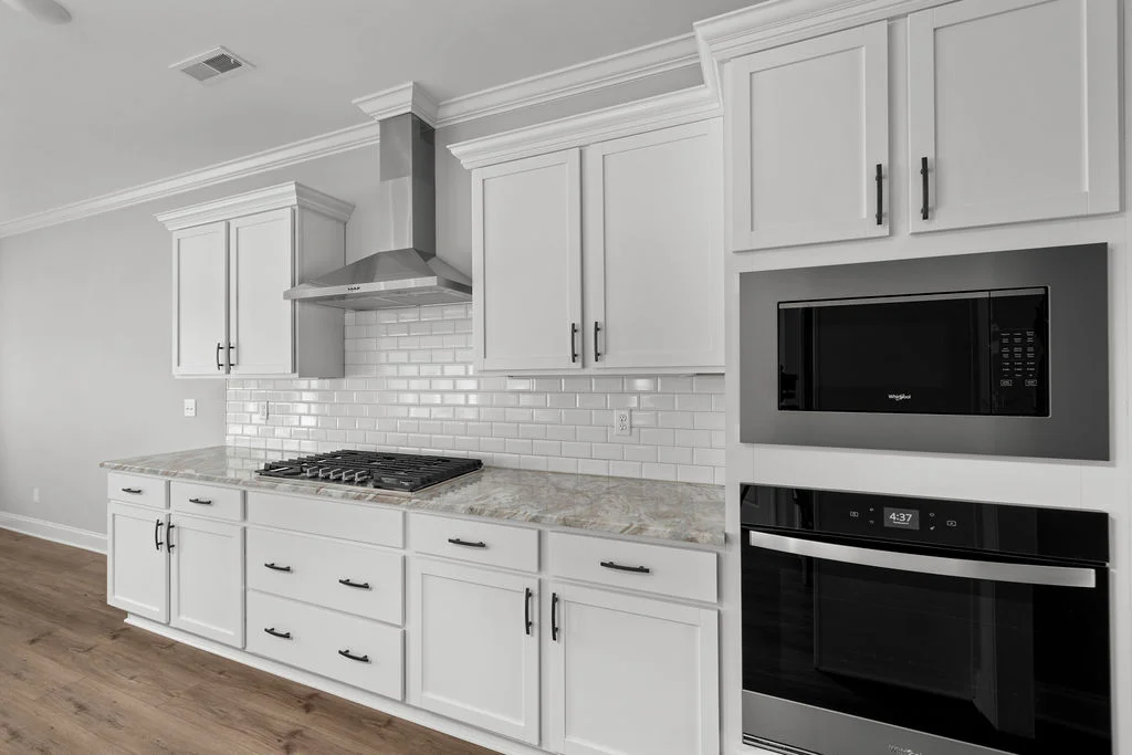 Home for sale. Modern kitchen with white cabinets, marble countertops, and stainless appliances by Pratt Home Builders in Chattanooga TN.