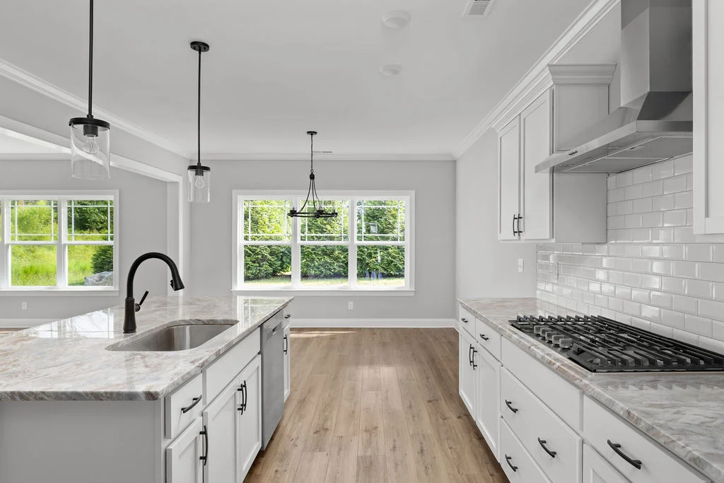 Modern kitchen by Pratt Home Builders in Chattanooga TN with marble countertops, large windows, hardwood floors, and stainless steel appliances.