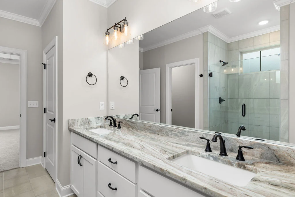 Elegant bathroom with marble countertop, dual sinks, and glass shower by Pratt Home Builders in Chattanooga TN.