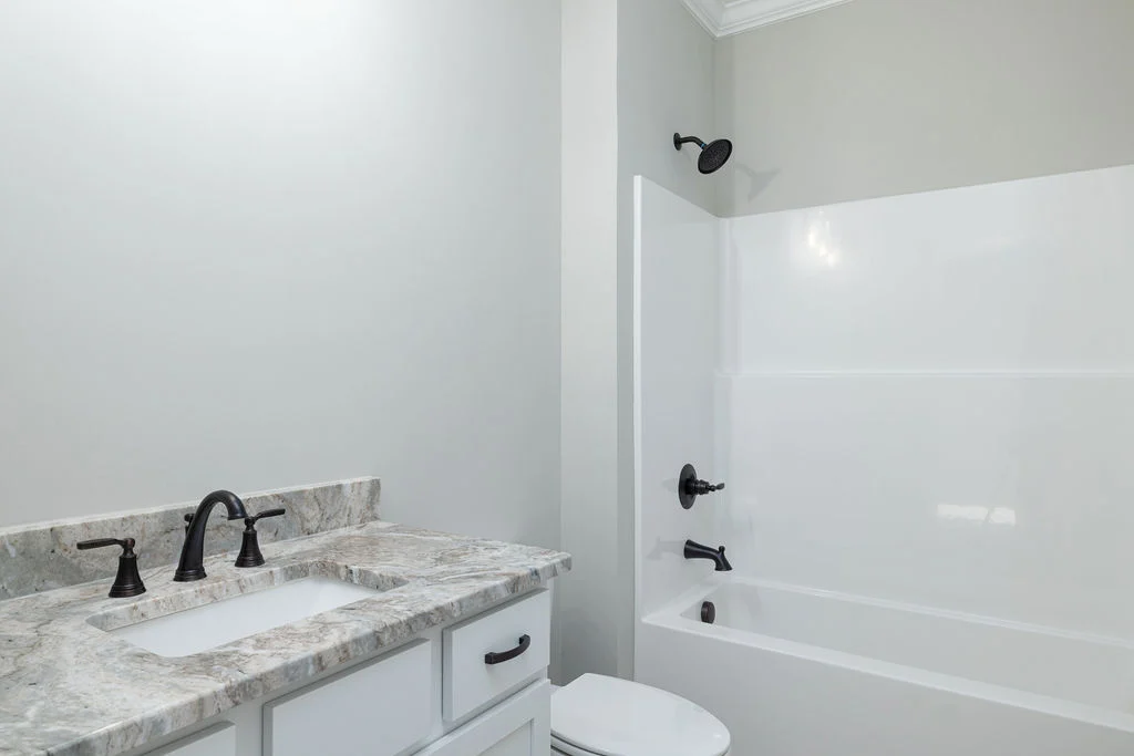 New home Soddy Daisy. Minimalist bathroom with white bathtub, marble vanity, and black fixtures by Pratt Home Builders in Chattanooga TN.