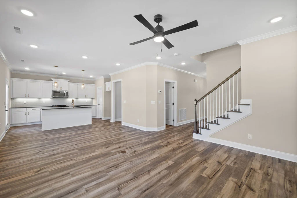 Open-concept kitchen and living area featuring hardwood floors, a central island, and staircase, by Pratt Home Builders in Chattanooga TN.