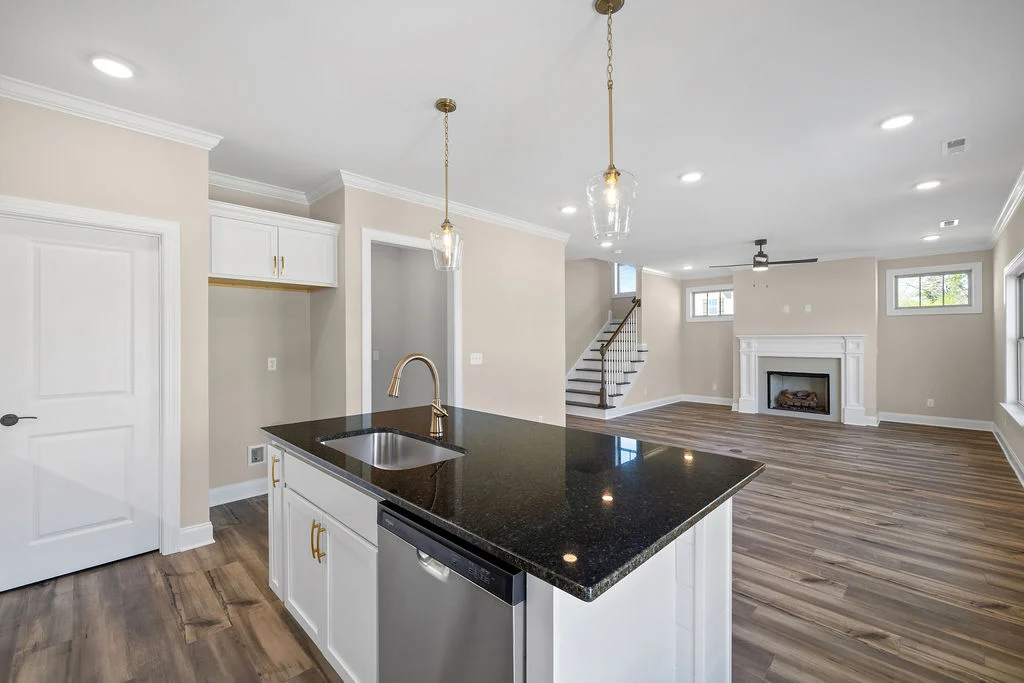 Modern kitchen and living space by Pratt Home Builders in Chattanooga TN, featuring dark countertop, pendant lights, and a cozy fireplace.