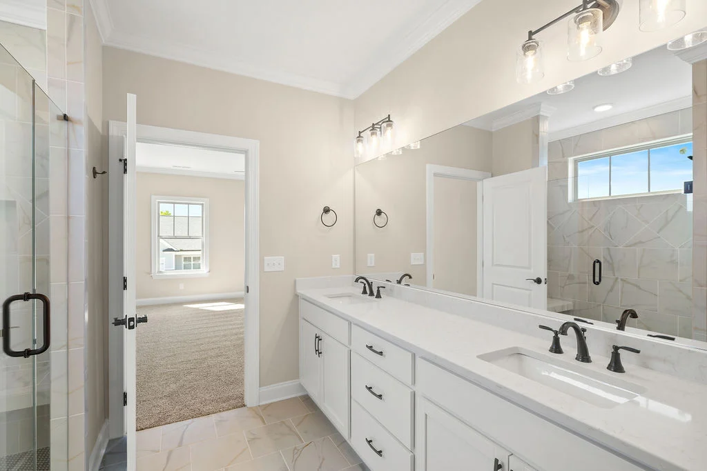 Spacious bathroom by Pratt Home Builders in Chattanooga TN, featuring a double vanity, large mirror, glass shower, and recessed lighting.