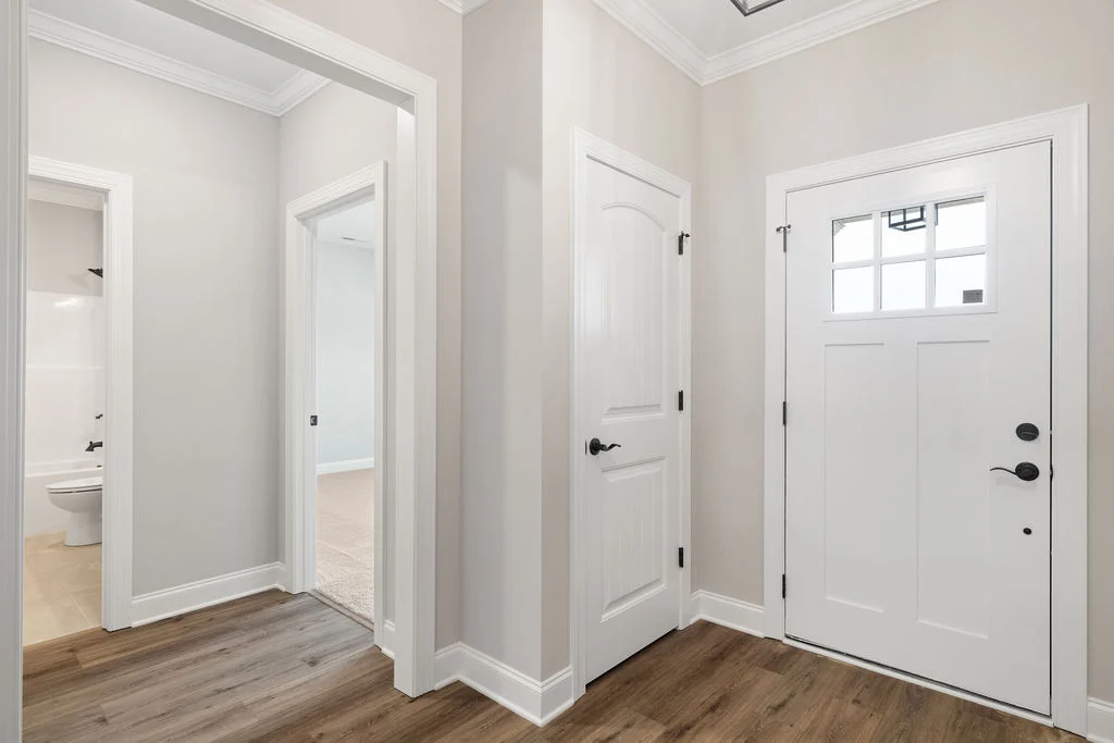 Bright entryway with wooden floor, white doors, and neutral walls by Pratt Home Builders in Chattanooga TN, leading to bathroom and rooms.