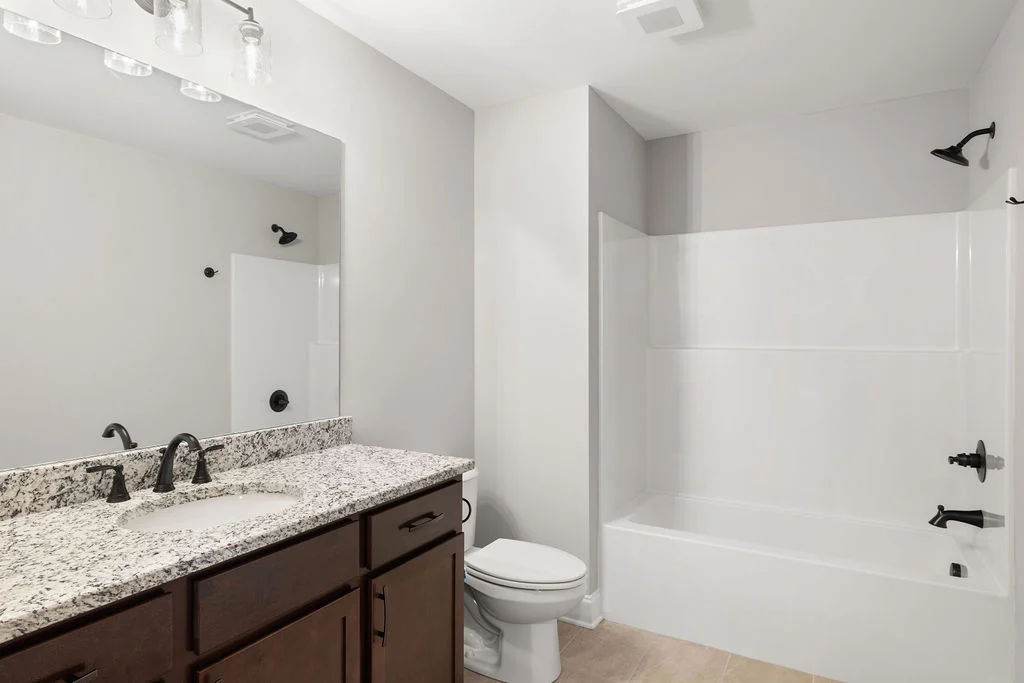 New Home Chattanooga TN. Modern bathroom featuring granite countertop, black fixtures, and a white tub by Pratt Home Builders.