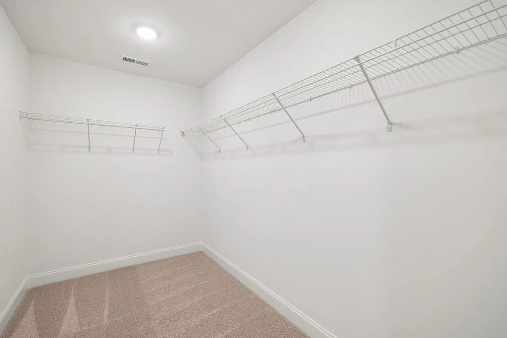 New Home Chattanooga TN. Spacious walk-in closet with beige carpet and metal shelving by Pratt Home Builders.