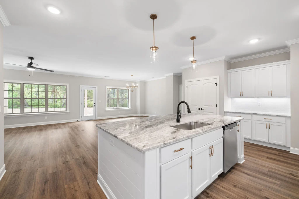 Modern kitchen and living space with marble countertop, wood floors, and large windows, designed by Pratt Home Builders in Chattanooga TN.