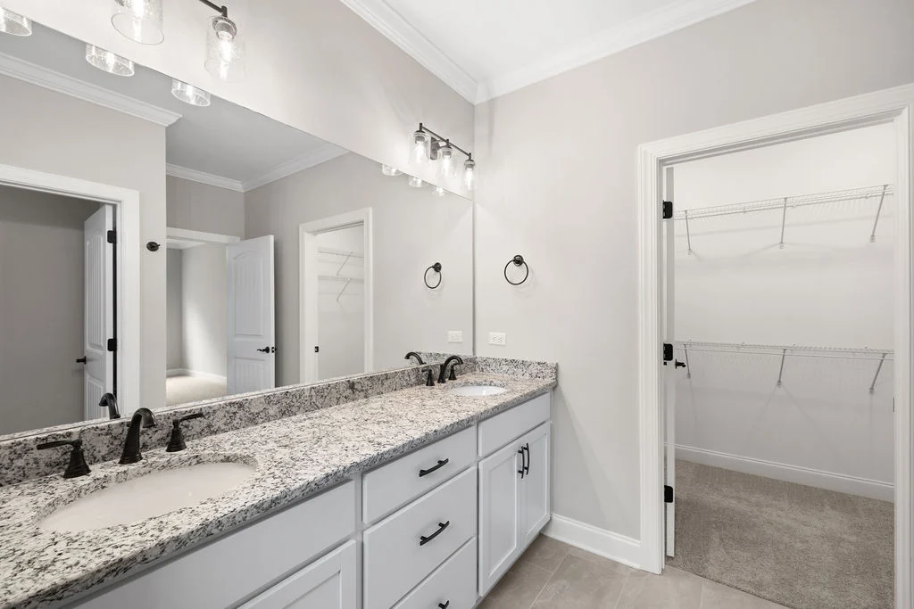 New Home Chattanooga TN. Elegant bathroom with granite double vanity, sleek fixtures, and spacious walk-in closet by Pratt Home Builders.
