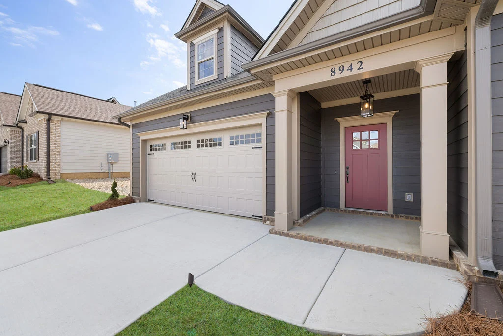 New Home Chattanooga TN. Modern house exterior with a pink front door and two-car garage, built by Pratt Home Builders.