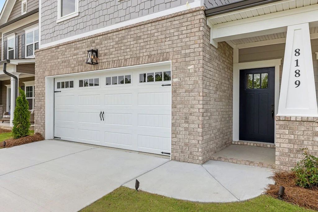 Modern home with brick exterior, white garage door, black front door, and house number 8189. Built by Pratt Home Builders in Chattanooga TN.