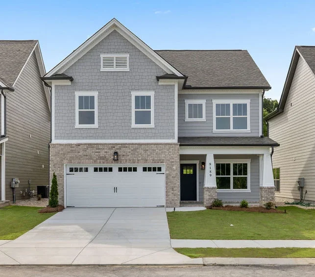 Modern two-story house with brick and siding exterior, double garage, built by Pratt Home Builders in Chattanooga TN, flanked by similar homes.
