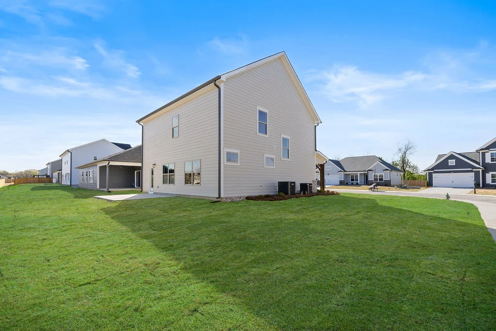 New Home Chattanooga TN. Modern beige house with manicured lawn under blue sky. Built by Pratt Home Builders.