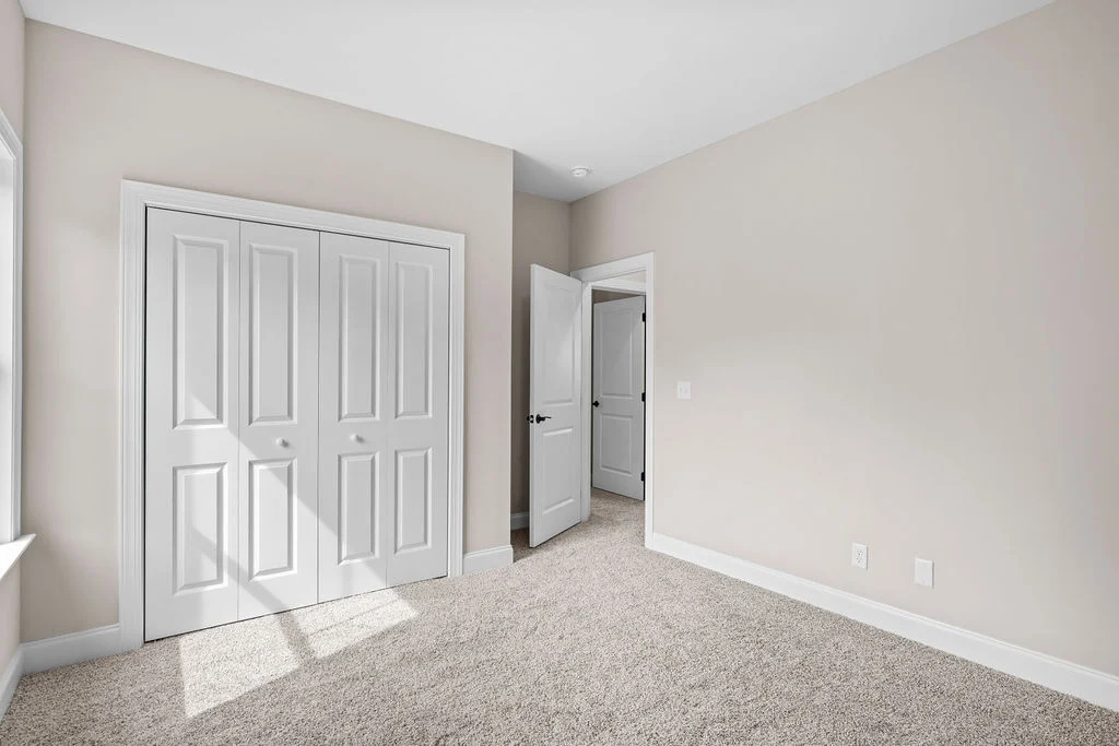 Bright room with beige walls, carpeted floor, and white closet doors. Designed by Pratt Home Builders in Chattanooga TN.