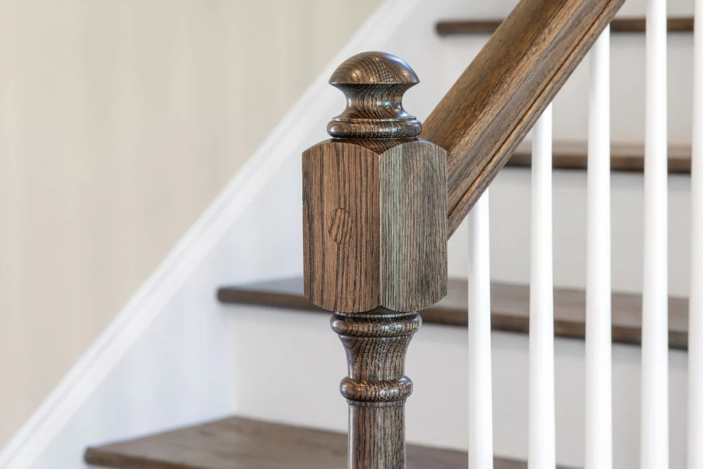 New home Chattanooga TN. Wooden staircase post detail with elegant dark finish, complementing white balusters by Pratt Home Builders.