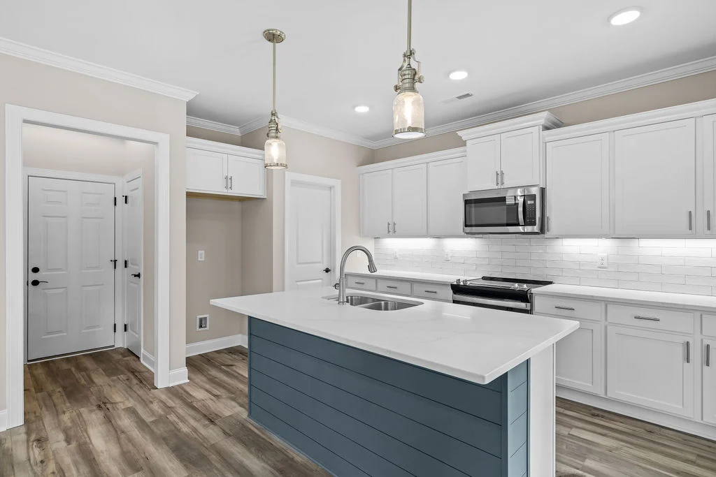 Modern kitchen with white cabinets, stainless steel appliances, blue island, and hardwood floors, designed by Pratt Home Builders in Chattanooga TN.