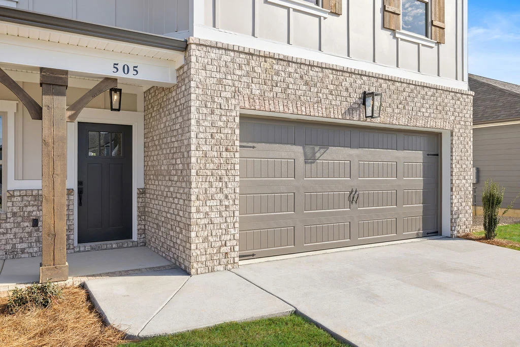 New Home Chattanooga TN. Modern home exterior by Pratt Home Builders, featuring a brick facade, gray door, and double garage.