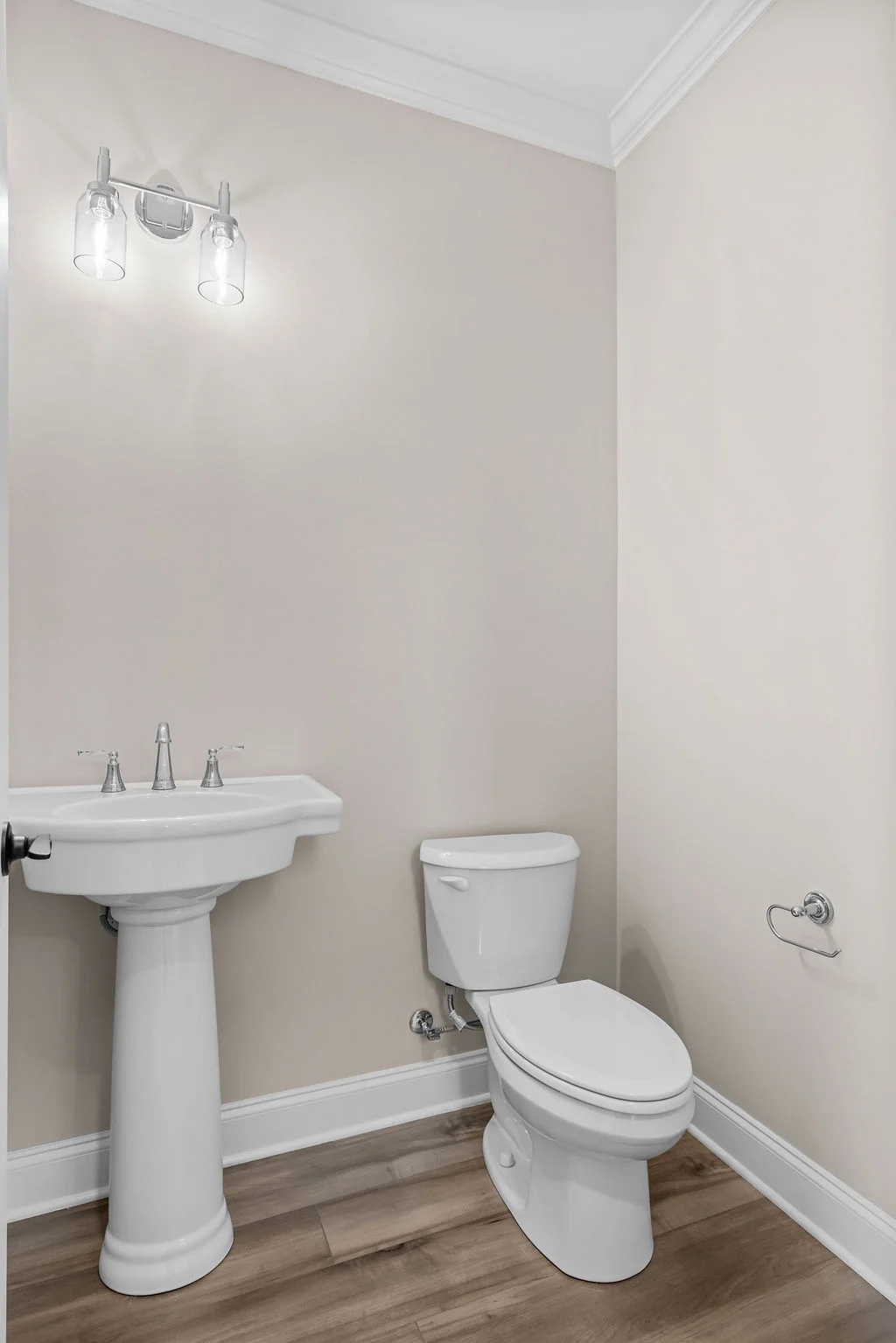 Modern bathroom with pedestal sink, toilet, and dual-light fixture. Designed by Pratt Home Builders in Chattanooga TN.