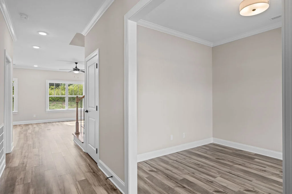 Empty modern room with wood flooring, beige walls, and recessed lighting, built by Pratt Home Builders in Chattanooga TN. Large window with nature vie