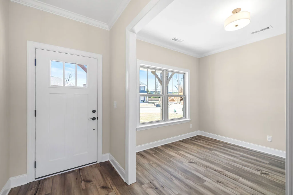 New Home Chattanooga TN. Bright foyer with light wood flooring and white front door, showcasing Pratt Home Builders.