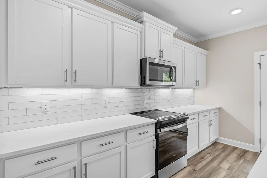Modern kitchen with white cabinets, subway tile backsplash, stainless steel appliances, and wood flooring by Pratt Home Builders in Chattanooga TN.