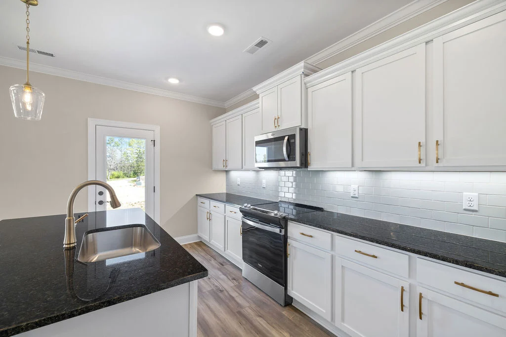 New Home Chattanooga TN. Modern kitchen with white cabinets, dark countertops, stainless steel appliances, and glass door. Built by Pratt Home Builders.