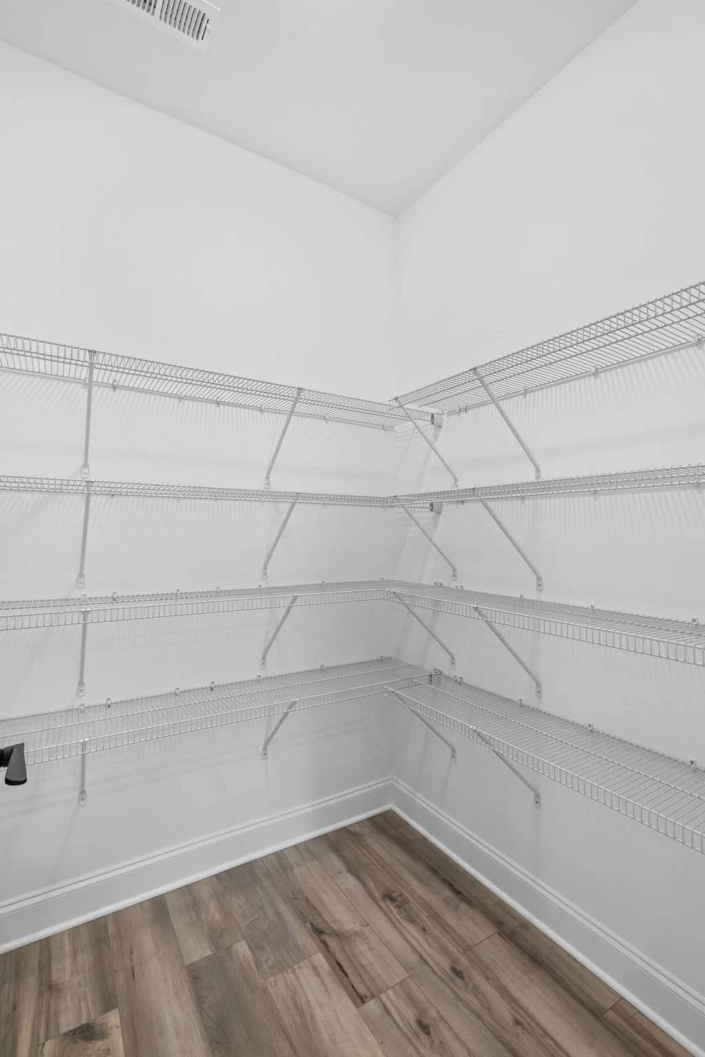 Empty walk-in pantry with multiple wire shelves and wood flooring, designed by Pratt Home Builders in Chattanooga TN.
