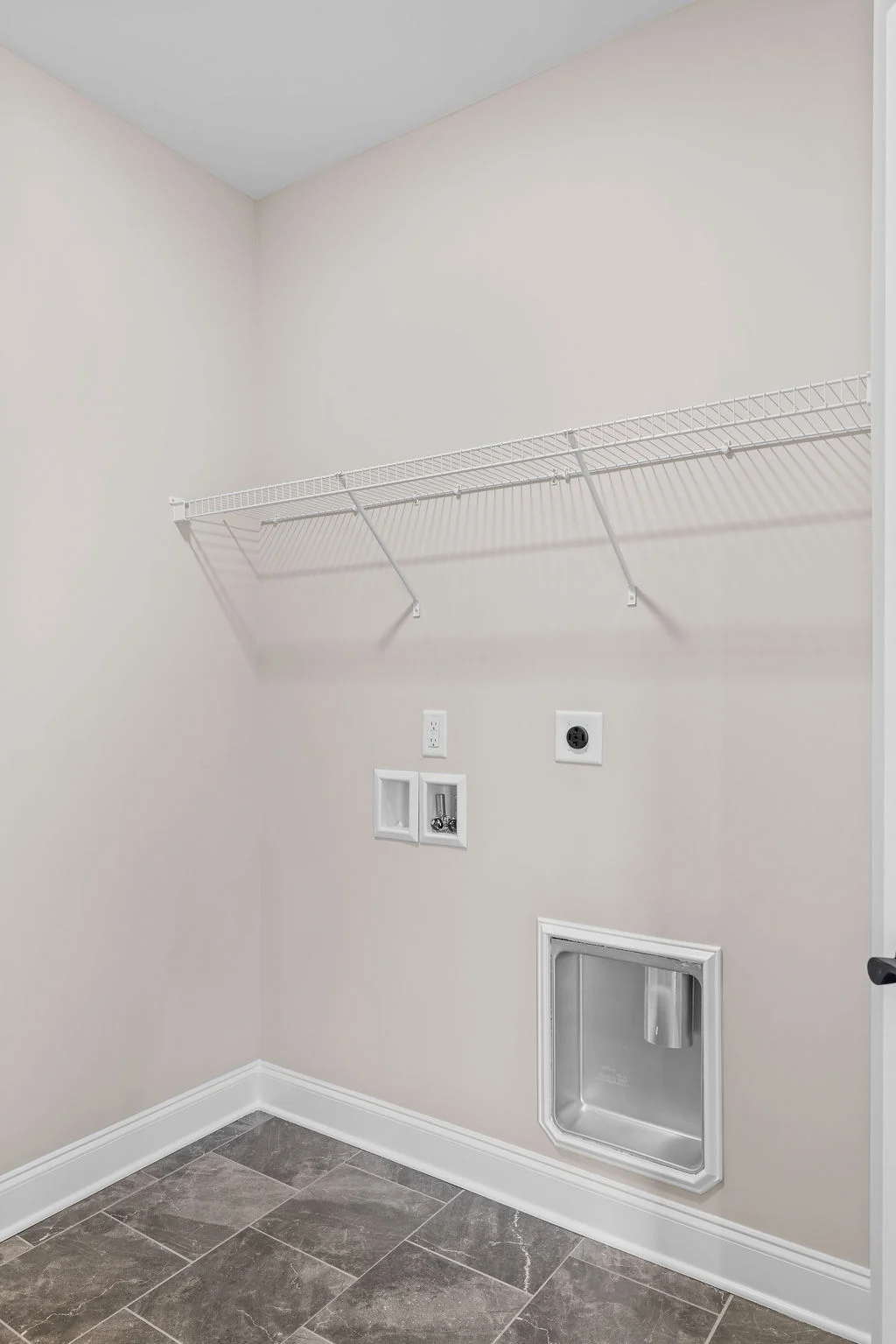 Laundry room with beige walls, tiled floor, wire shelf, and utility hookups. Built by Pratt Home Builders in Chattanooga TN.