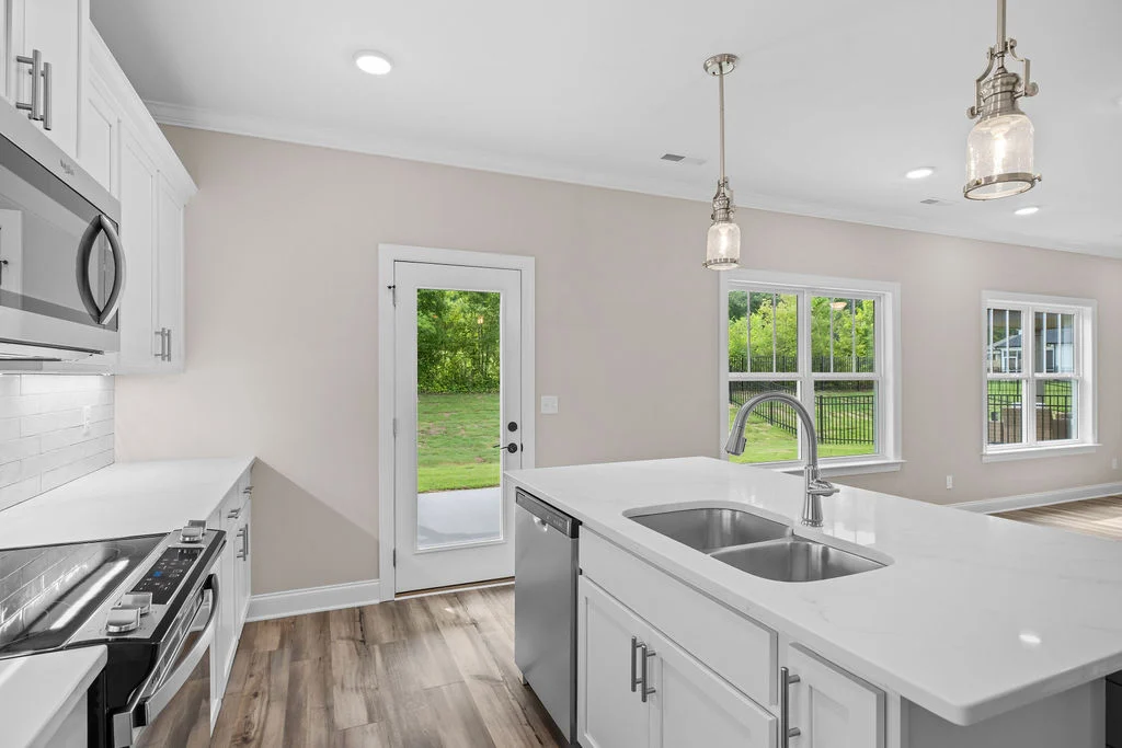 Modern kitchen by Pratt Home Builders in Chattanooga TN, featuring white cabinets, stainless steel appliances, and large windows with backyard view.