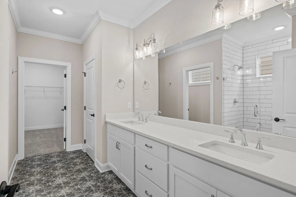 Elegant bathroom with dual sinks, sleek tile shower, and spacious walk-in closet. Built by Pratt Home Builders in Chattanooga, TN.