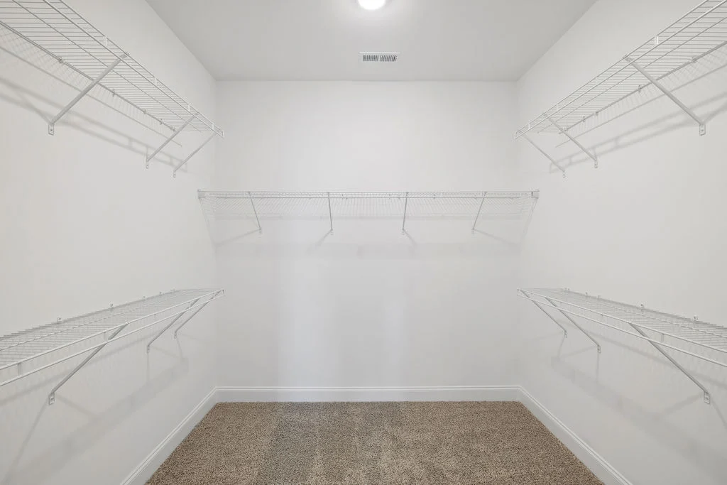 New Home Chattanooga TN. Empty walk-in closet with multiple white wire shelves and carpeted floor, built by Pratt Home Builders.