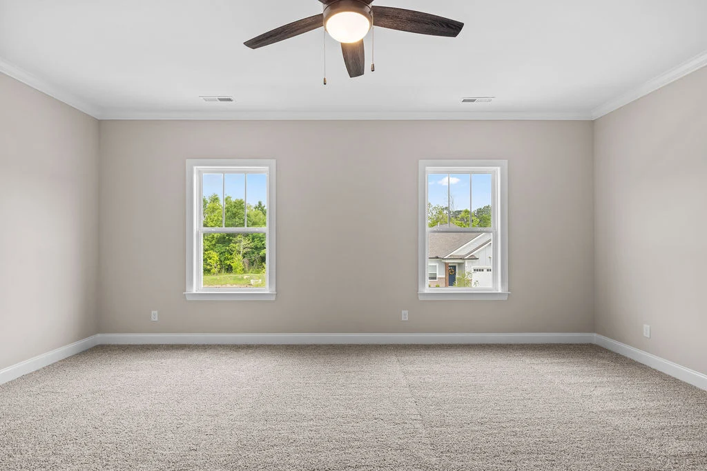 Spacious, carpeted room with two windows and ceiling fan, showcasing Pratt Home Builders in Chattanooga TN.