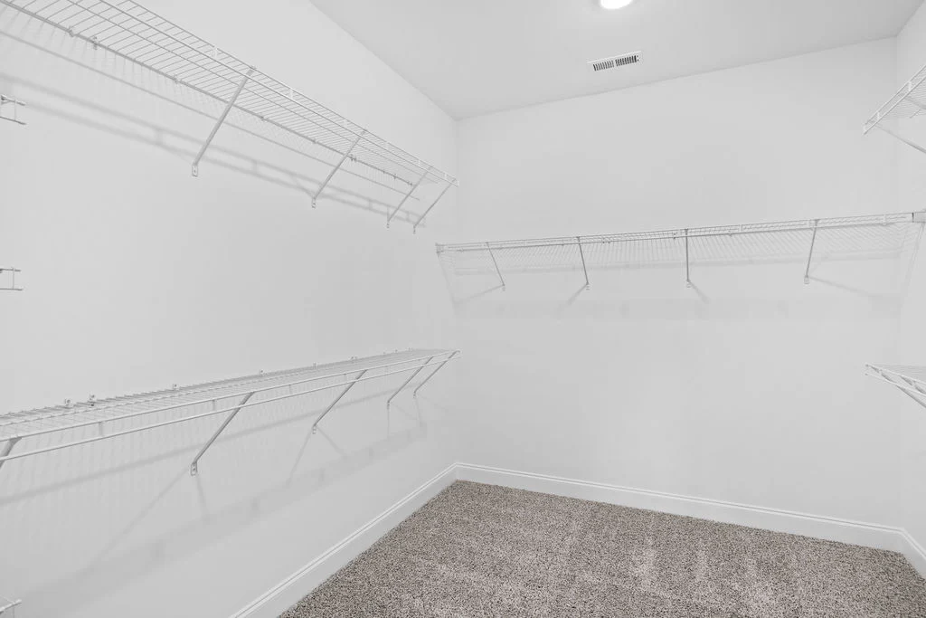 Spacious walk-in closet with white wire shelving and carpeted floor by Pratt Home Builders in Chattanooga TN.