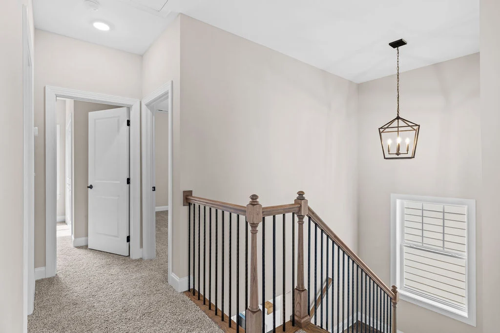 Bright stairway and hallway with modern lighting and carpeted floor by Pratt Home Builders in Chattanooga TN.
