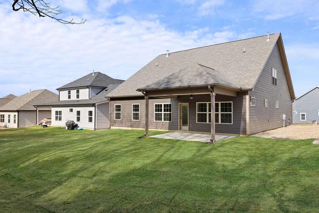 New Home Chattanooga TN. Spacious backyard view of a modern home with gray siding and covered patio, built by Pratt Home Builders.