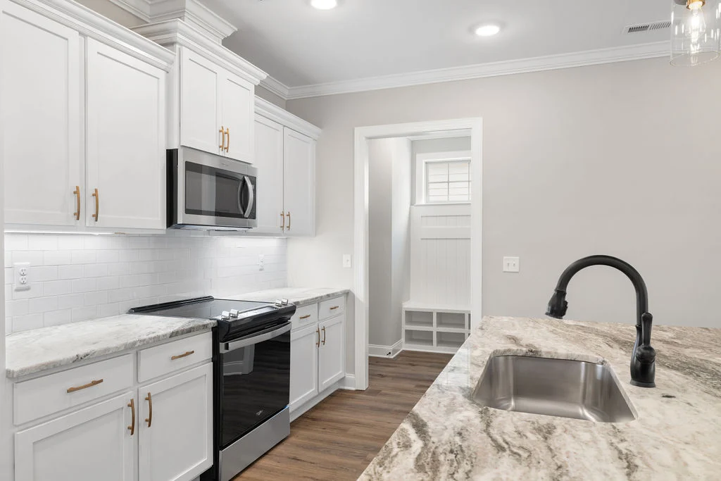 New Home Chattanooga TN. Modern kitchen with white cabinets, granite countertops, stainless steel appliances, and black faucet by Pratt Home Builders.