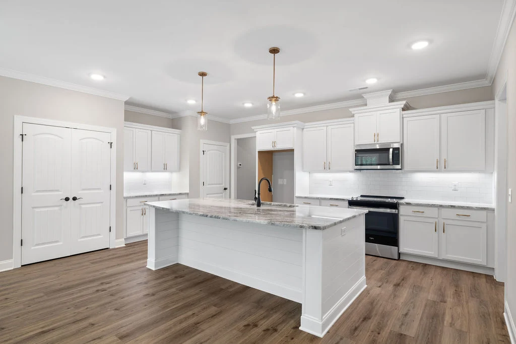 New Home Chattanooga TN. Spacious kitchen with white cabinets, granite island, wood floors, stainless appliances; built by Pratt Home Builders.