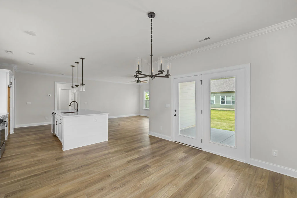 Spacious open-concept kitchen and dining area with hardwood floors, modern lighting, glass doors to patio. Built by Pratt Home Builders in Chattanooga