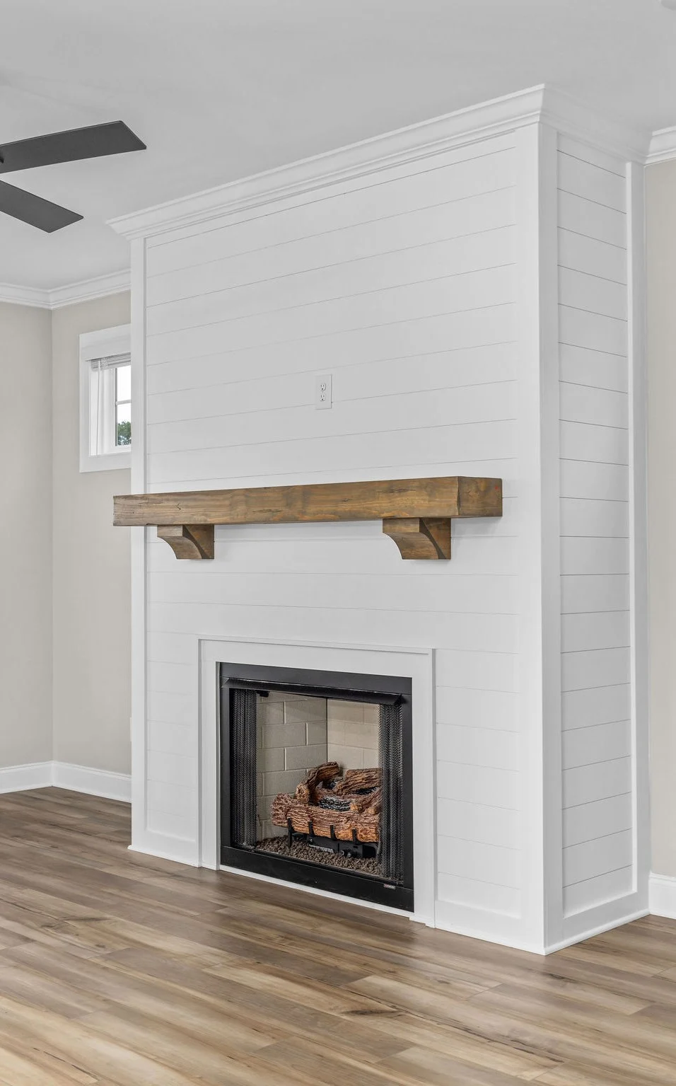 Elegant white shiplap fireplace with wooden mantel, showcasing modern interior design by Pratt Home Builders in Chattanooga TN.