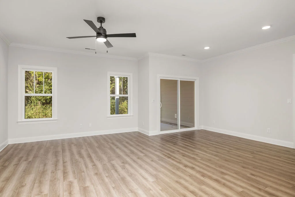 Spacious, light-filled room with wood flooring, ceiling fan, and sliding glass door by Pratt Home Builders in Chattanooga TN.