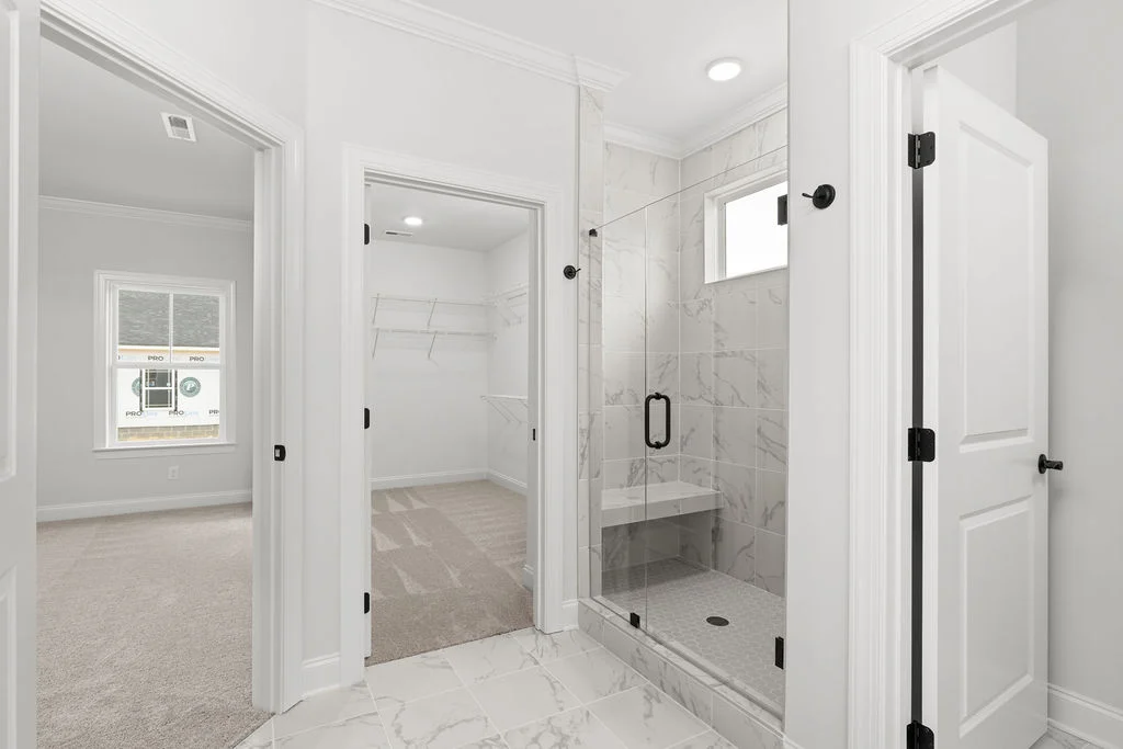 New Home Chattanooga TN. Modern bathroom with tiled shower, adjacent walk-in closet, and bedroom by Pratt Home Builders.