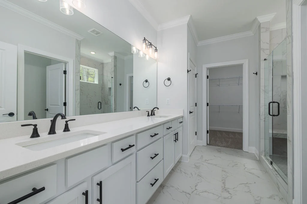 Spacious bathroom by Pratt Home Builders in Chattanooga TN, featuring dual sinks, sleek fixtures, marble floors, and a walk-in shower.