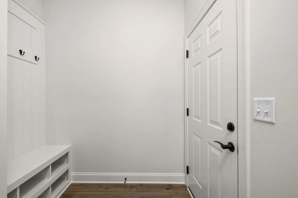 Modern entryway with a white door, coat hooks, and storage bench, showcasing Pratt Home Builders in Chattanooga TN.