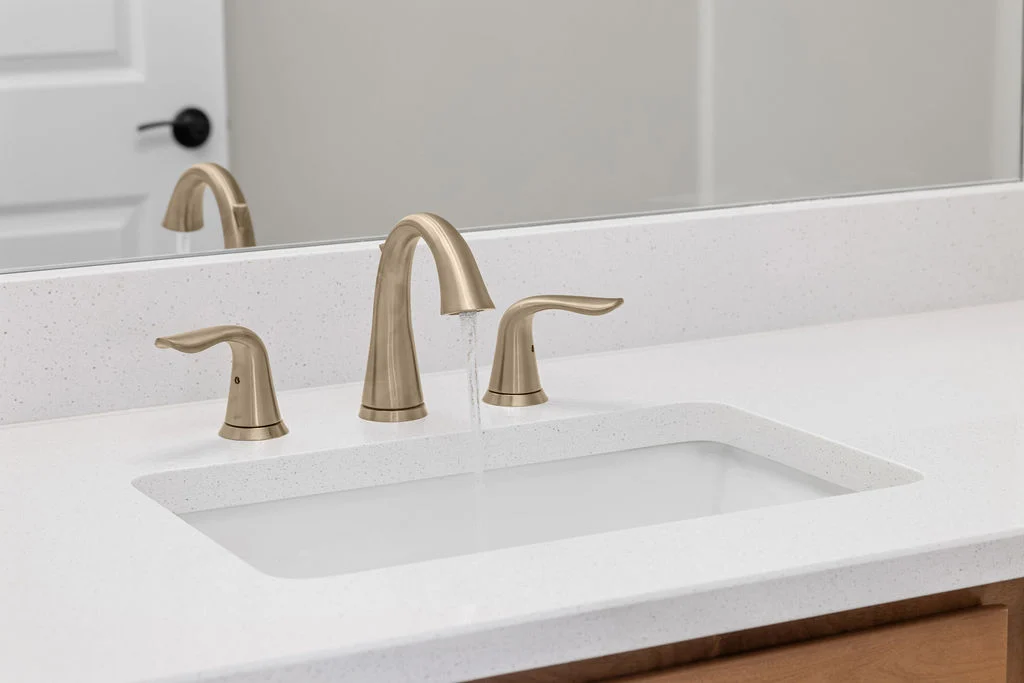 Modern bathroom sink with brass faucet on sleek white countertop by Pratt Home Builders in Chattanooga TN.