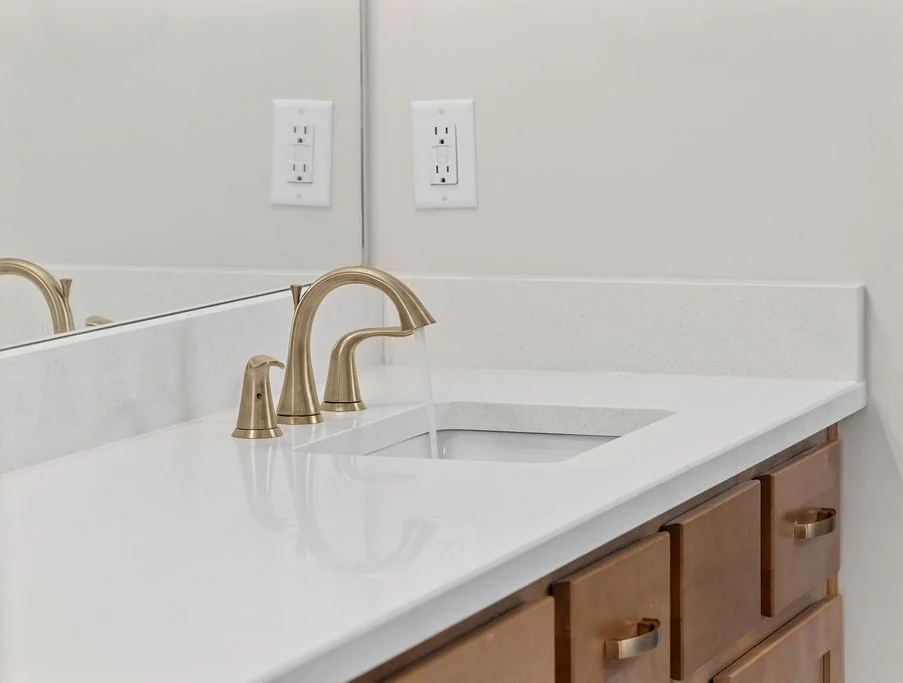 Modern bathroom vanity with gold faucet, white countertop, and wooden drawers by Pratt Home Builders in Chattanooga TN.