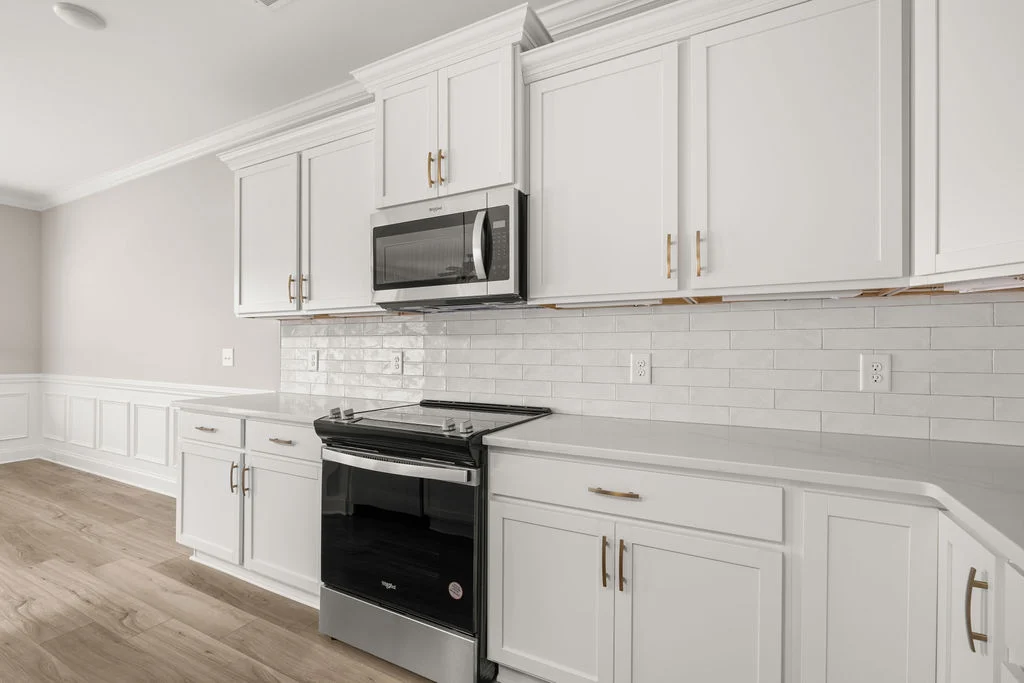 New Home Chattanooga TN. Modern kitchen with white cabinets, stainless steel appliances, subway tile backsplash, and hardwood floors by Pratt Home Builders.