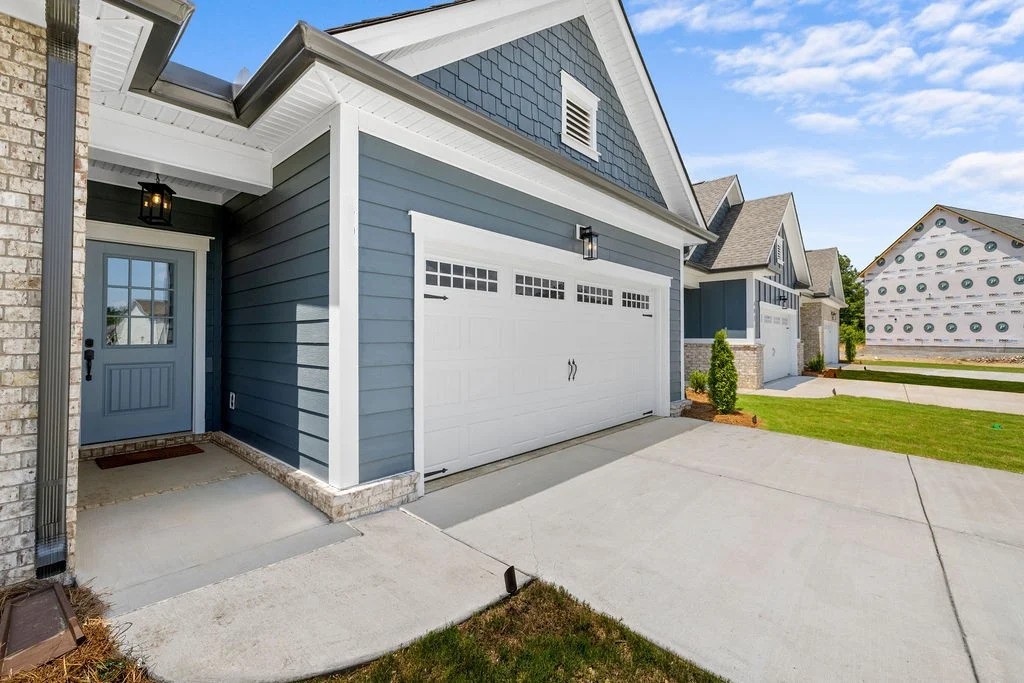 Modern suburban home with gray siding, white garage, and entry door. Construction in progress nearby. Pratt Home Builders in Chattanooga TN.