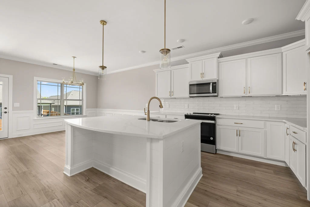 New Home chattanooga TN. Modern kitchen by Pratt Home Builders featuring white cabinetry, large island, pendant lights, and wood-look flooring.